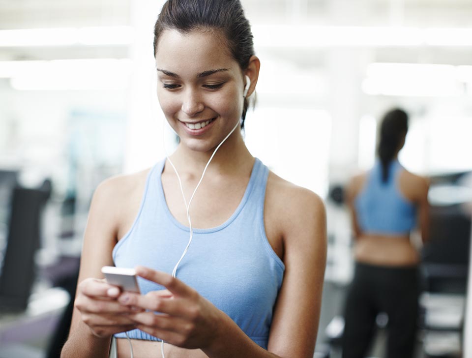Woman, earphones and listening to music at gym, phone and stream